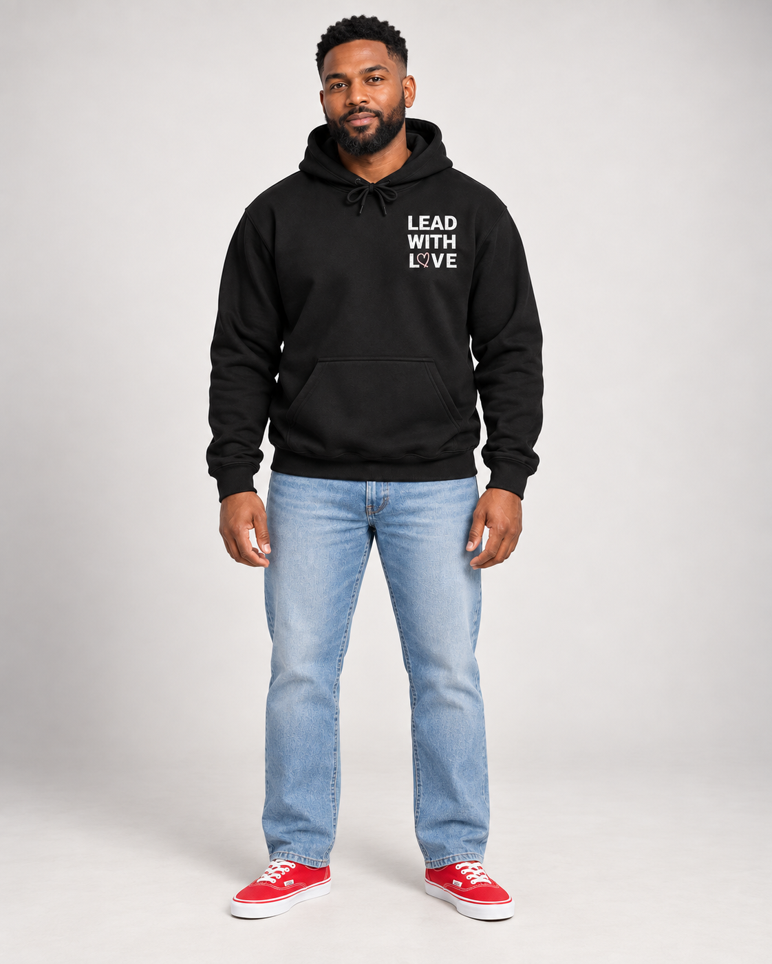 Full body view of black Lead With Love hoodie with light wash jeans and red Vans